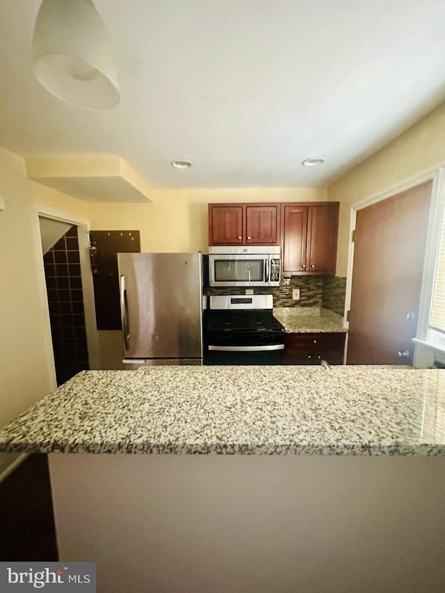 kitchen featuring tasteful backsplash, light stone counters, and stainless steel appliances