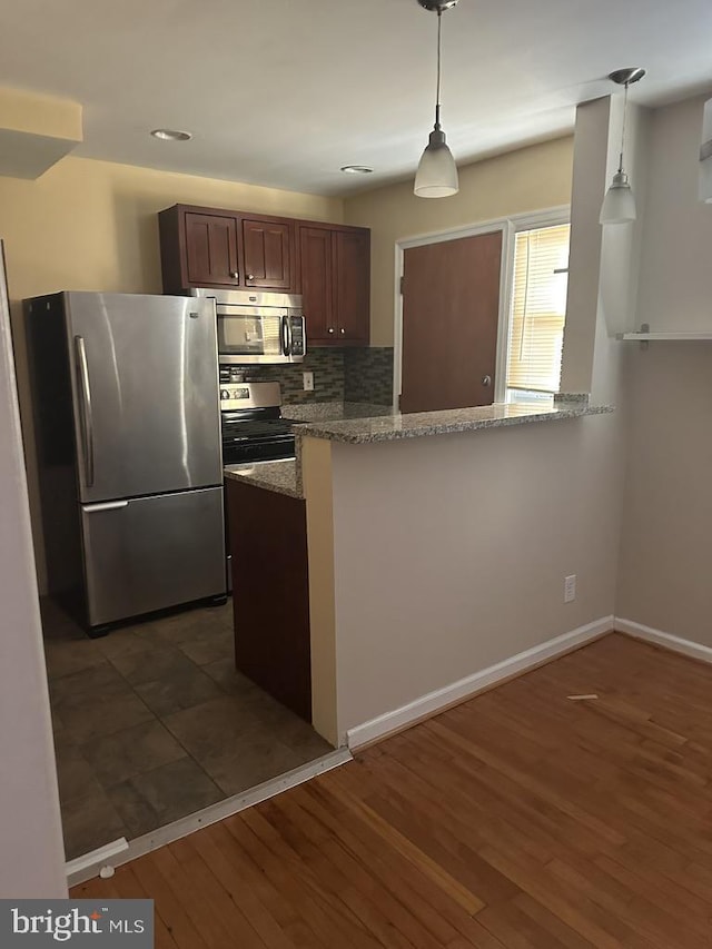 kitchen with kitchen peninsula, stainless steel appliances, and decorative light fixtures