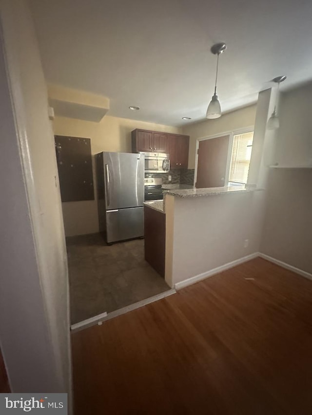 kitchen with kitchen peninsula, light stone countertops, tasteful backsplash, stainless steel appliances, and dark hardwood / wood-style floors