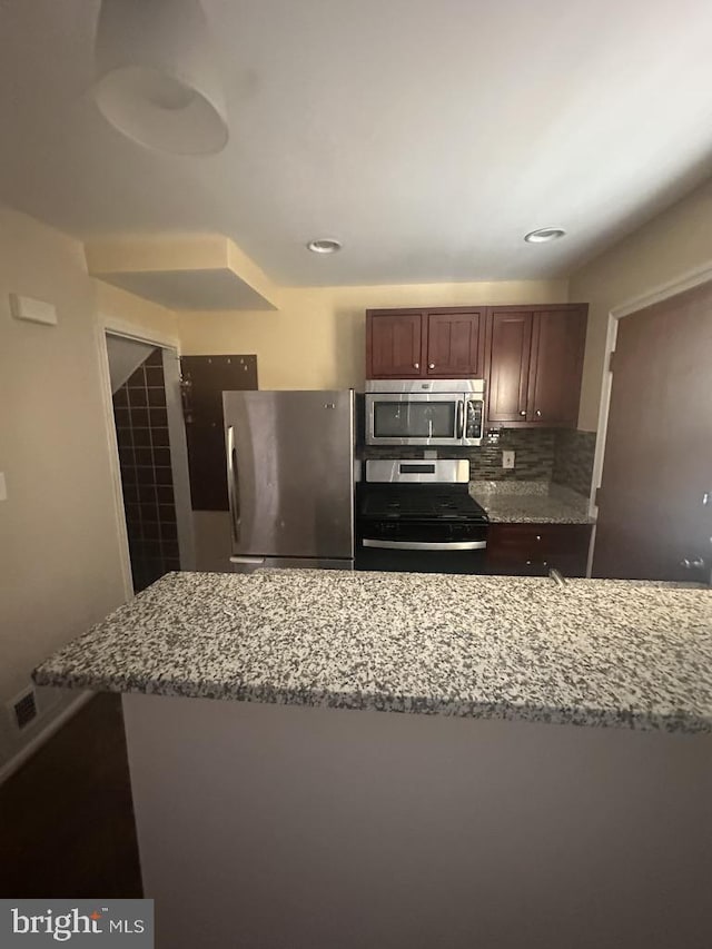 kitchen featuring decorative backsplash, light stone counters, and stainless steel appliances