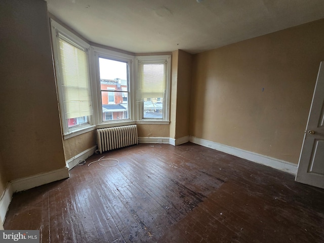 empty room featuring radiator heating unit and hardwood / wood-style flooring