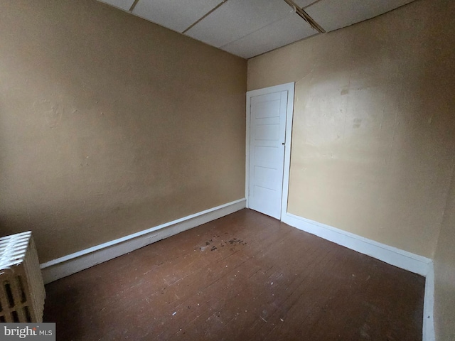 unfurnished room featuring a drop ceiling and dark wood-type flooring