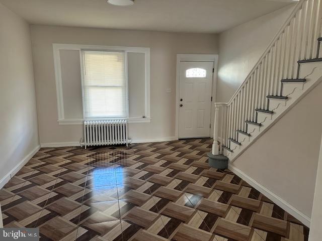 entrance foyer featuring radiator heating unit and dark parquet floors