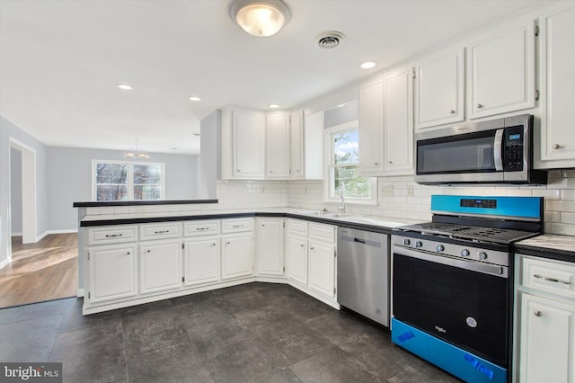 kitchen featuring kitchen peninsula, appliances with stainless steel finishes, sink, a notable chandelier, and white cabinets