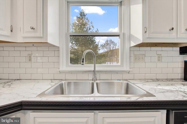 kitchen featuring backsplash, light stone countertops, sink, and white cabinets