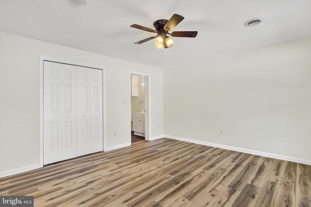 unfurnished bedroom with connected bathroom, ceiling fan, a closet, and hardwood / wood-style floors