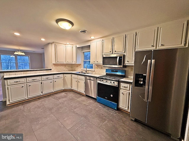 kitchen featuring white cabinetry, sink, stainless steel appliances, tasteful backsplash, and a chandelier