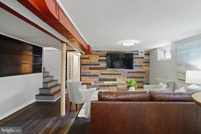 living room with dark wood-type flooring and wooden walls