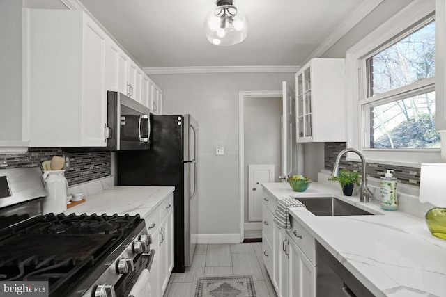 kitchen with white cabinetry, sink, light stone counters, and stainless steel appliances