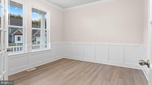 empty room featuring a wealth of natural light, french doors, light hardwood / wood-style floors, and ornamental molding