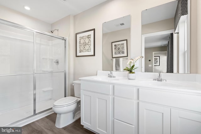 bathroom with toilet, a shower with door, vanity, and hardwood / wood-style floors