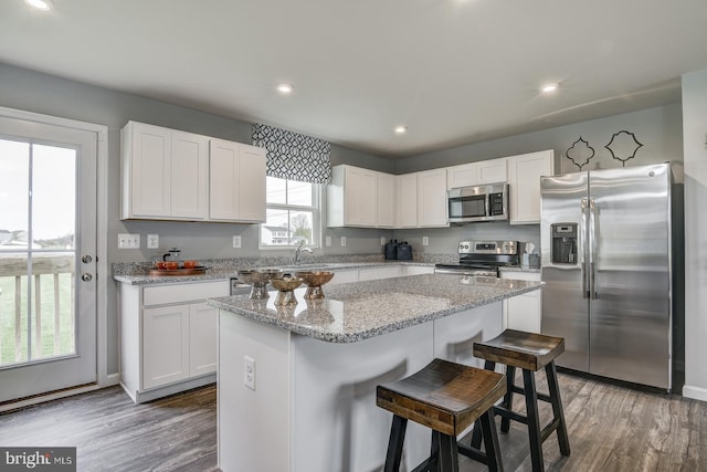 kitchen featuring a kitchen island, white cabinets, appliances with stainless steel finishes, and a kitchen breakfast bar