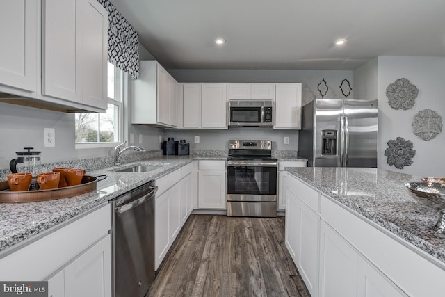 kitchen with sink, white cabinetry, light stone counters, dark hardwood / wood-style flooring, and appliances with stainless steel finishes