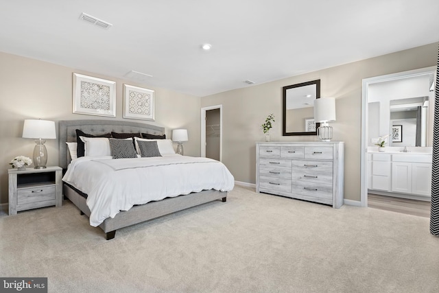 bedroom with light colored carpet, a spacious closet, and connected bathroom