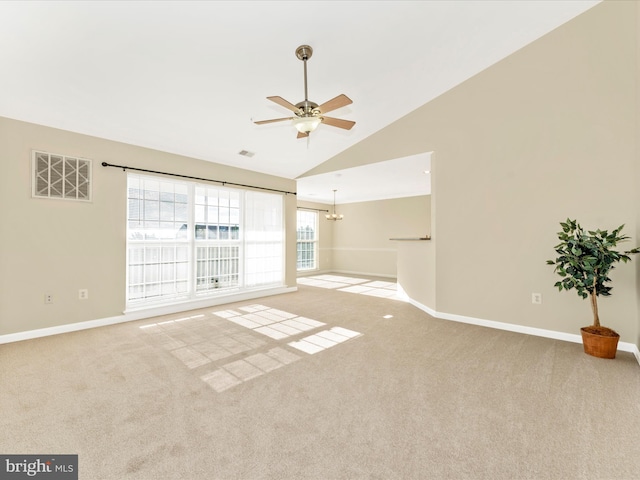 unfurnished room with ceiling fan with notable chandelier, light colored carpet, and vaulted ceiling