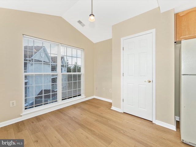 empty room featuring light wood-type flooring and vaulted ceiling