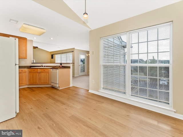 kitchen with white appliances, sink, hanging light fixtures, vaulted ceiling, and light hardwood / wood-style floors