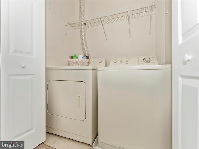 clothes washing area with washing machine and dryer and light tile patterned floors