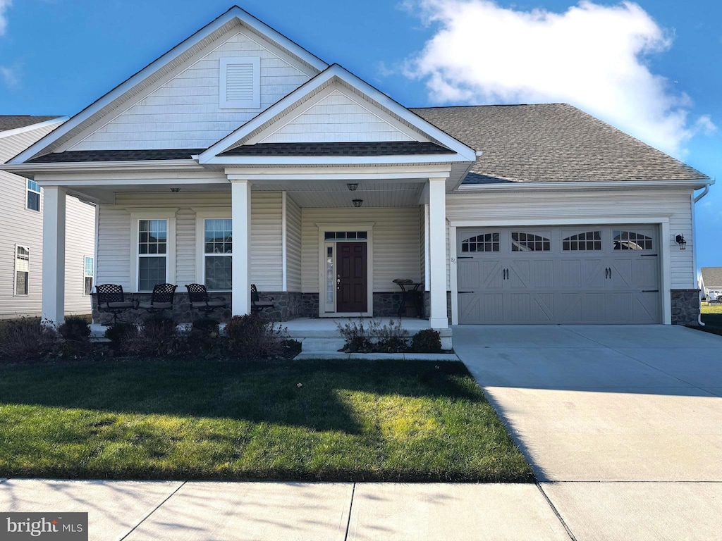 craftsman-style home featuring a porch, a garage, and a front yard