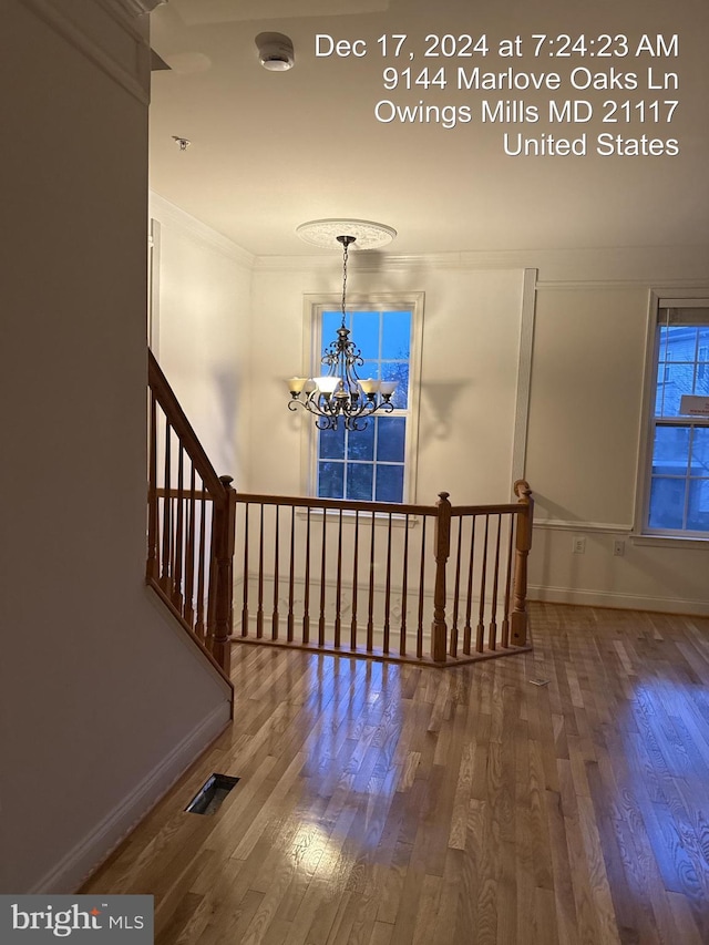 stairway with hardwood / wood-style flooring, an inviting chandelier, and ornamental molding