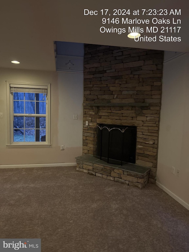 unfurnished living room with carpet floors and a stone fireplace