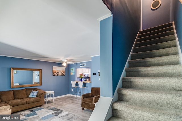 staircase with hardwood / wood-style flooring, ceiling fan, and ornamental molding