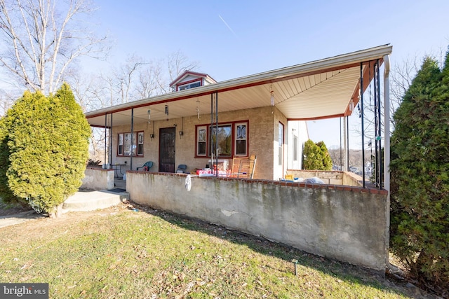 rear view of house with a lawn and a porch