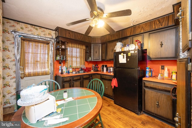 kitchen with black fridge, dark brown cabinets, a textured ceiling, ceiling fan, and light hardwood / wood-style floors