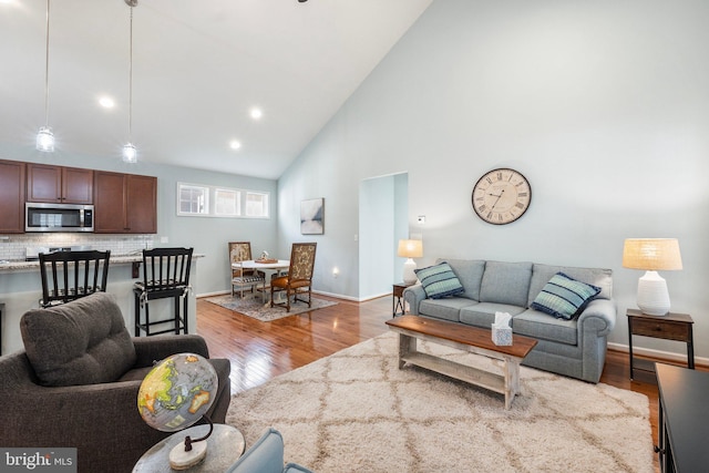 living room with light hardwood / wood-style flooring and high vaulted ceiling