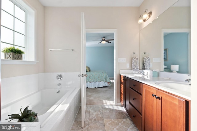 bathroom featuring tiled tub, ceiling fan, and vanity