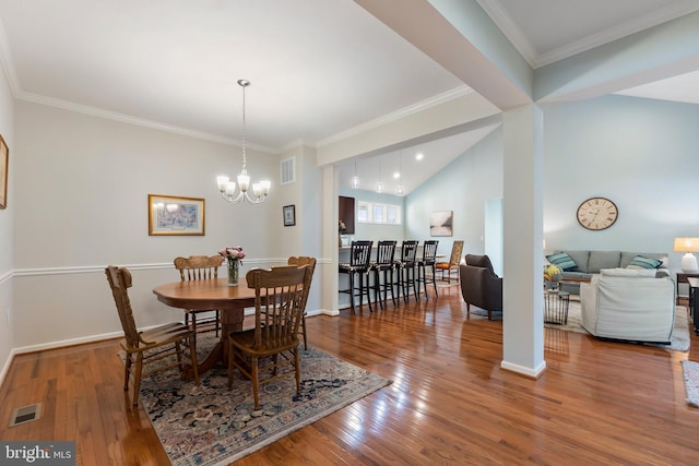 dining room with a chandelier, wood-type flooring, ornamental molding, and vaulted ceiling