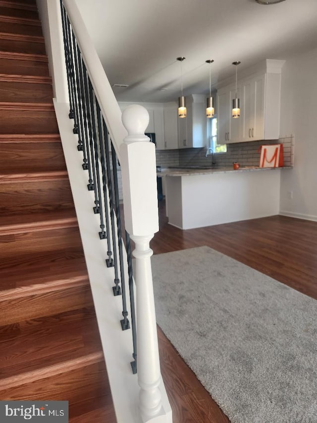 stairway with sink and hardwood / wood-style flooring