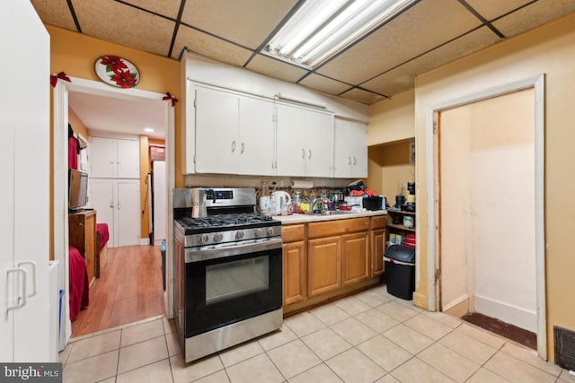 kitchen with light tile patterned flooring, sink, gas stove, and a drop ceiling