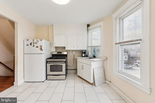 kitchen with white cabinetry, white fridge, sink, and stainless steel range with gas cooktop