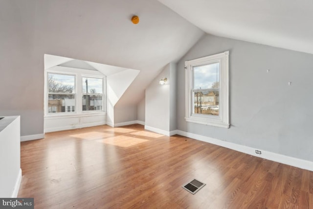 additional living space featuring lofted ceiling and light hardwood / wood-style floors