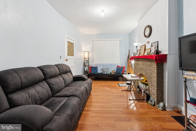 living room featuring a brick fireplace and wood-type flooring