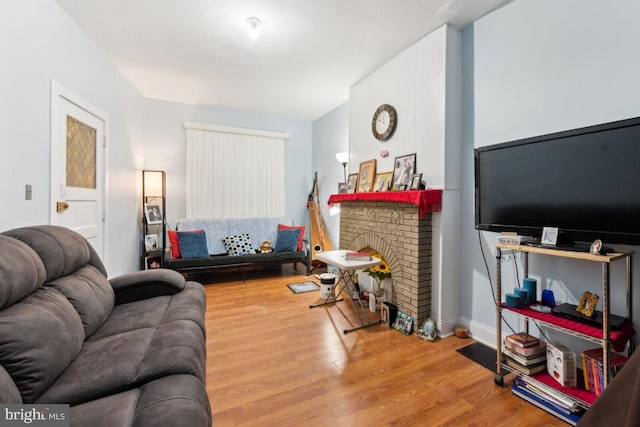 living room featuring wood-type flooring and a brick fireplace