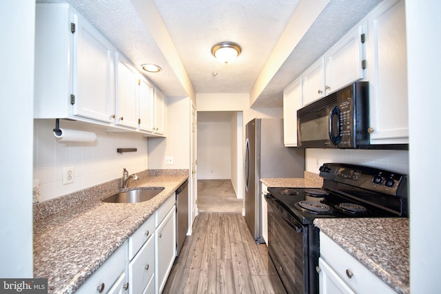 kitchen with backsplash, black appliances, sink, light wood-type flooring, and white cabinetry