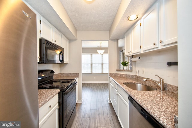 kitchen with black appliances, dark hardwood / wood-style floors, white cabinets, and sink