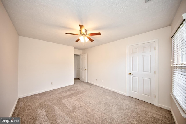 unfurnished bedroom featuring ceiling fan, light colored carpet, and a textured ceiling