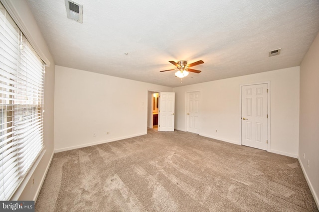 empty room featuring light carpet, a textured ceiling, and ceiling fan