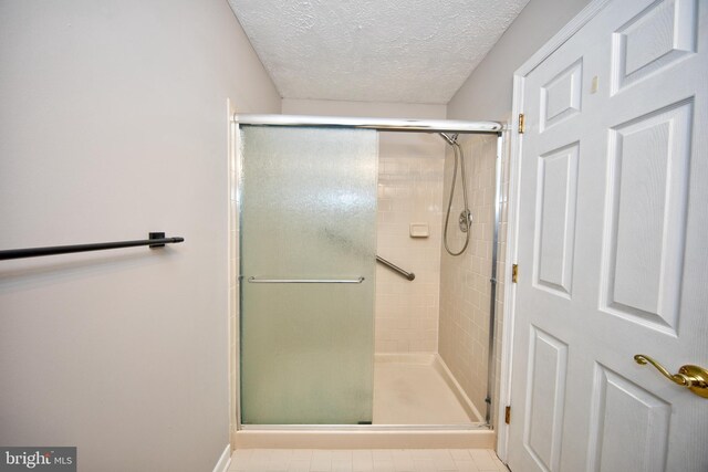 bathroom with tile patterned flooring, a textured ceiling, and walk in shower