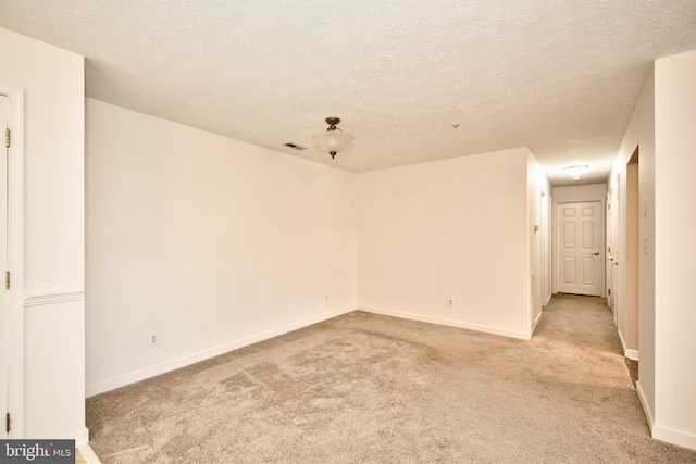 spare room featuring light carpet and a textured ceiling