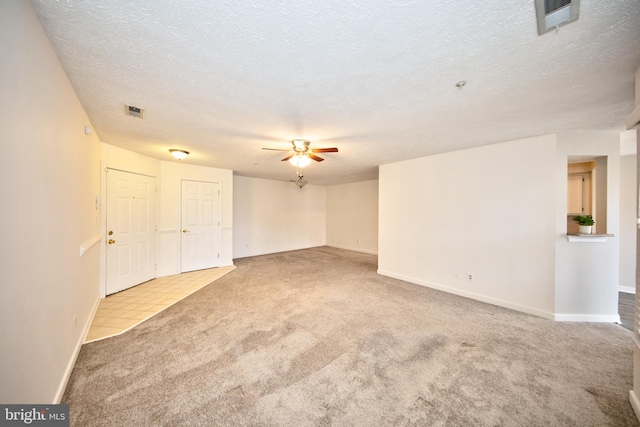 empty room with a textured ceiling, light colored carpet, and ceiling fan