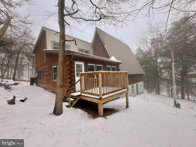 snow covered back of property with a deck