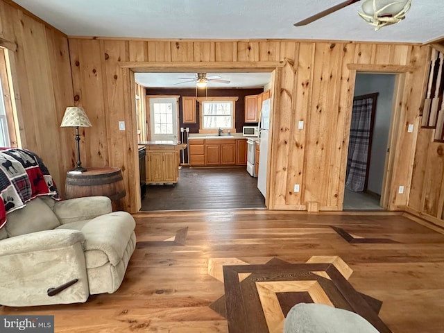 living room featuring wooden walls, sink, ceiling fan, and hardwood / wood-style flooring