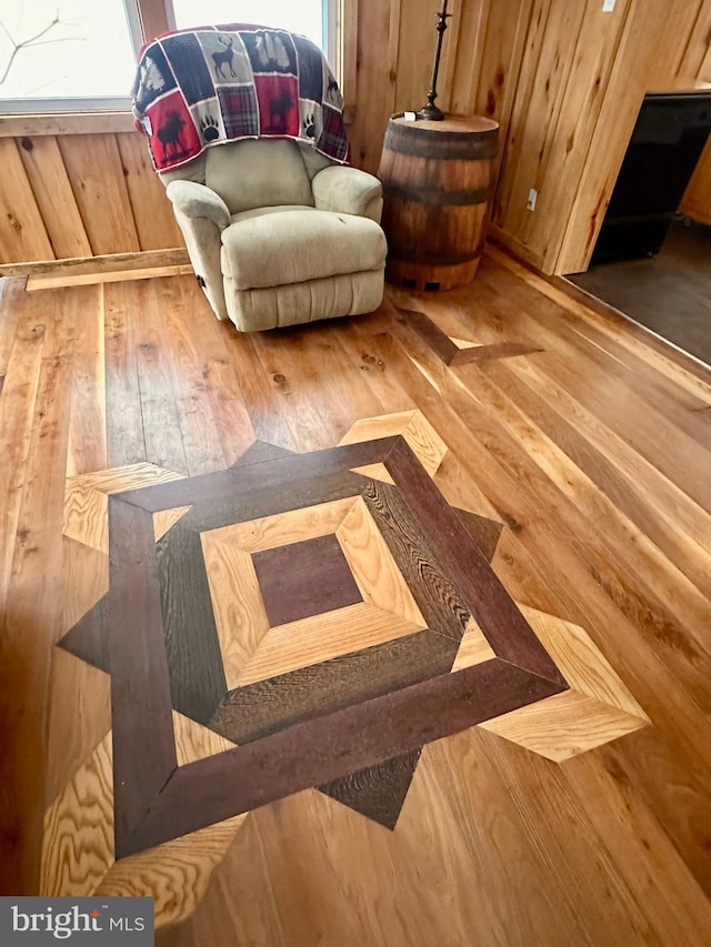 living area with hardwood / wood-style floors and wooden walls