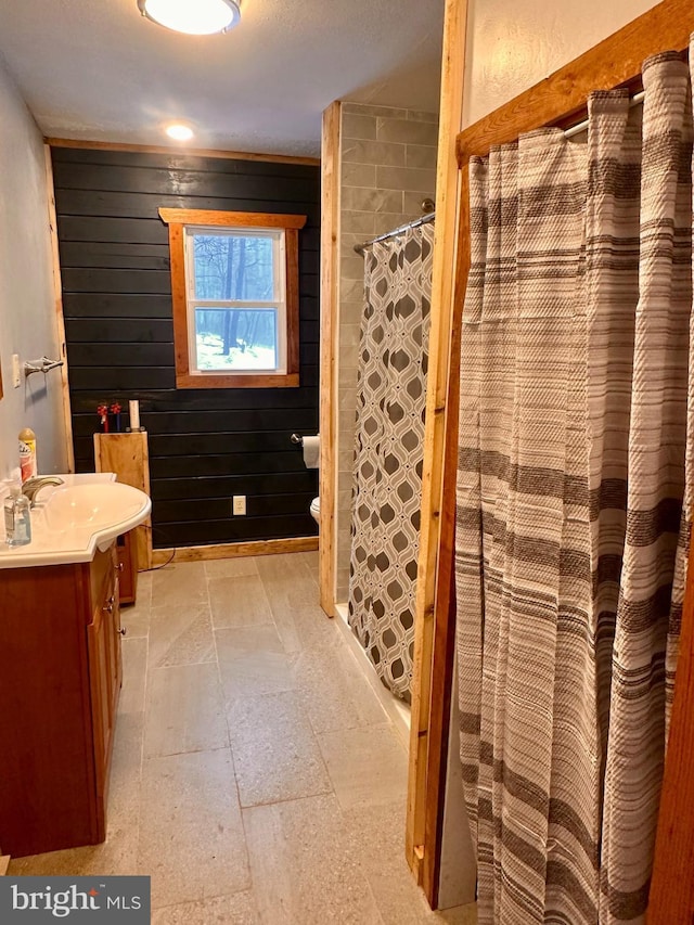 bathroom featuring wooden walls, toilet, vanity, and a shower with shower curtain