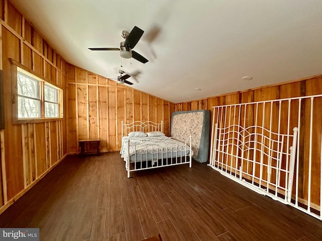 unfurnished bedroom with lofted ceiling, dark hardwood / wood-style floors, ceiling fan, and wooden walls