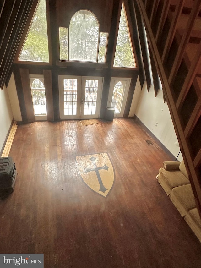 unfurnished living room featuring a high ceiling, hardwood / wood-style flooring, and french doors